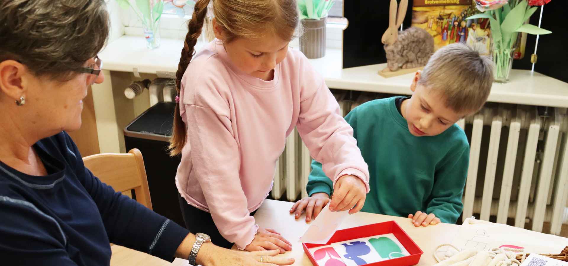 Mehrere Kinder und Erwachsene gestalten zusammen kreative Aufgaben am Tisch