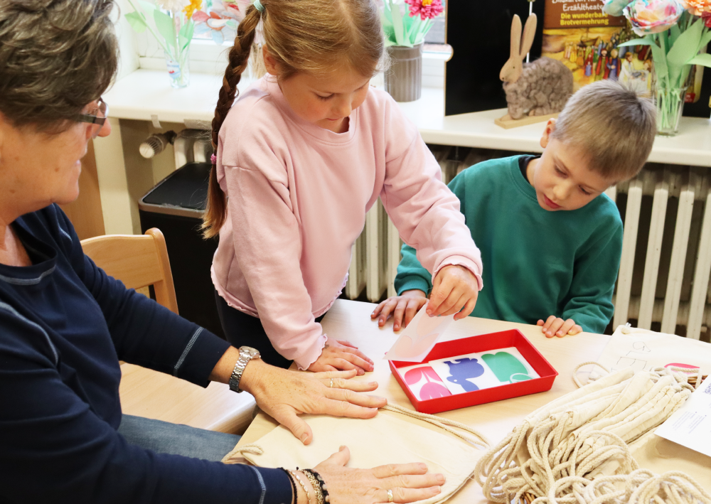 Mehrere Kinder und Erwachsene gestalten zusammen kreative Aufgaben am Tisch
