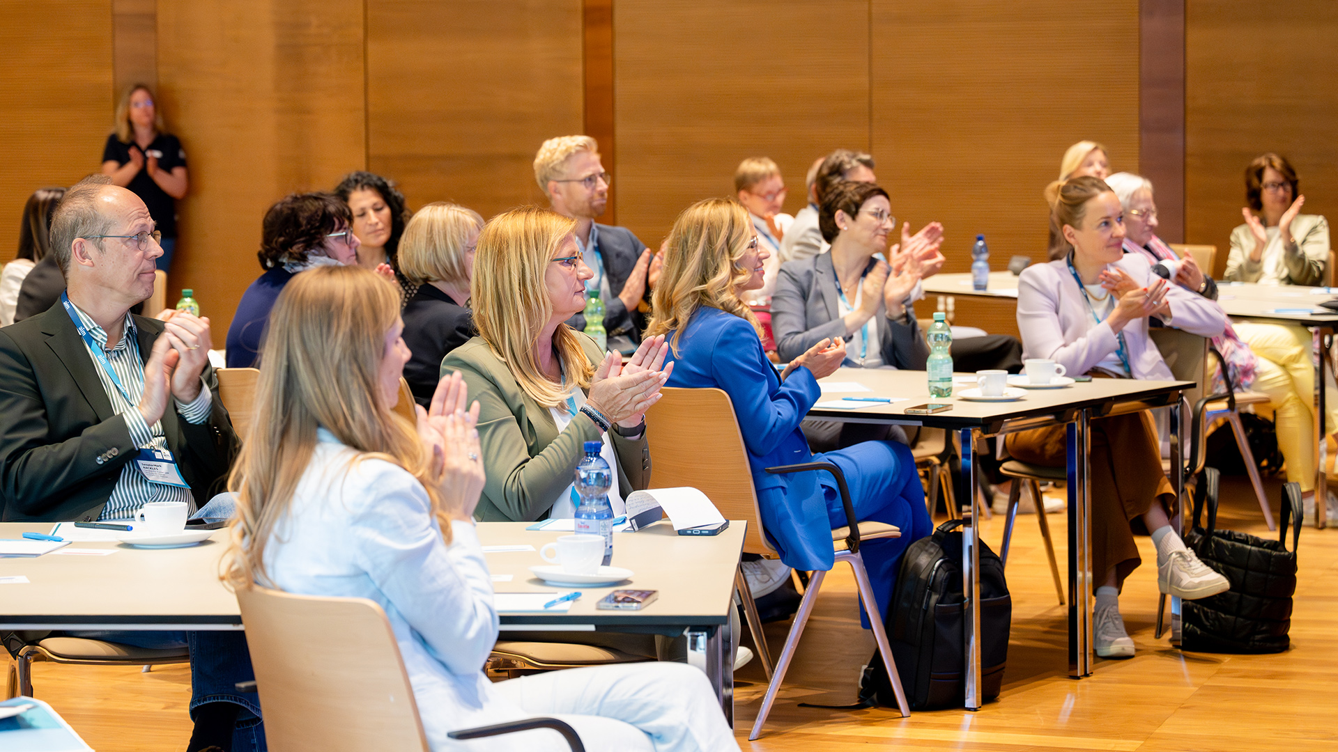 Teilnehmende des Nationalen Forums Frühe Bildung 2026 verfolgen eine Veranstaltung und applaudieren