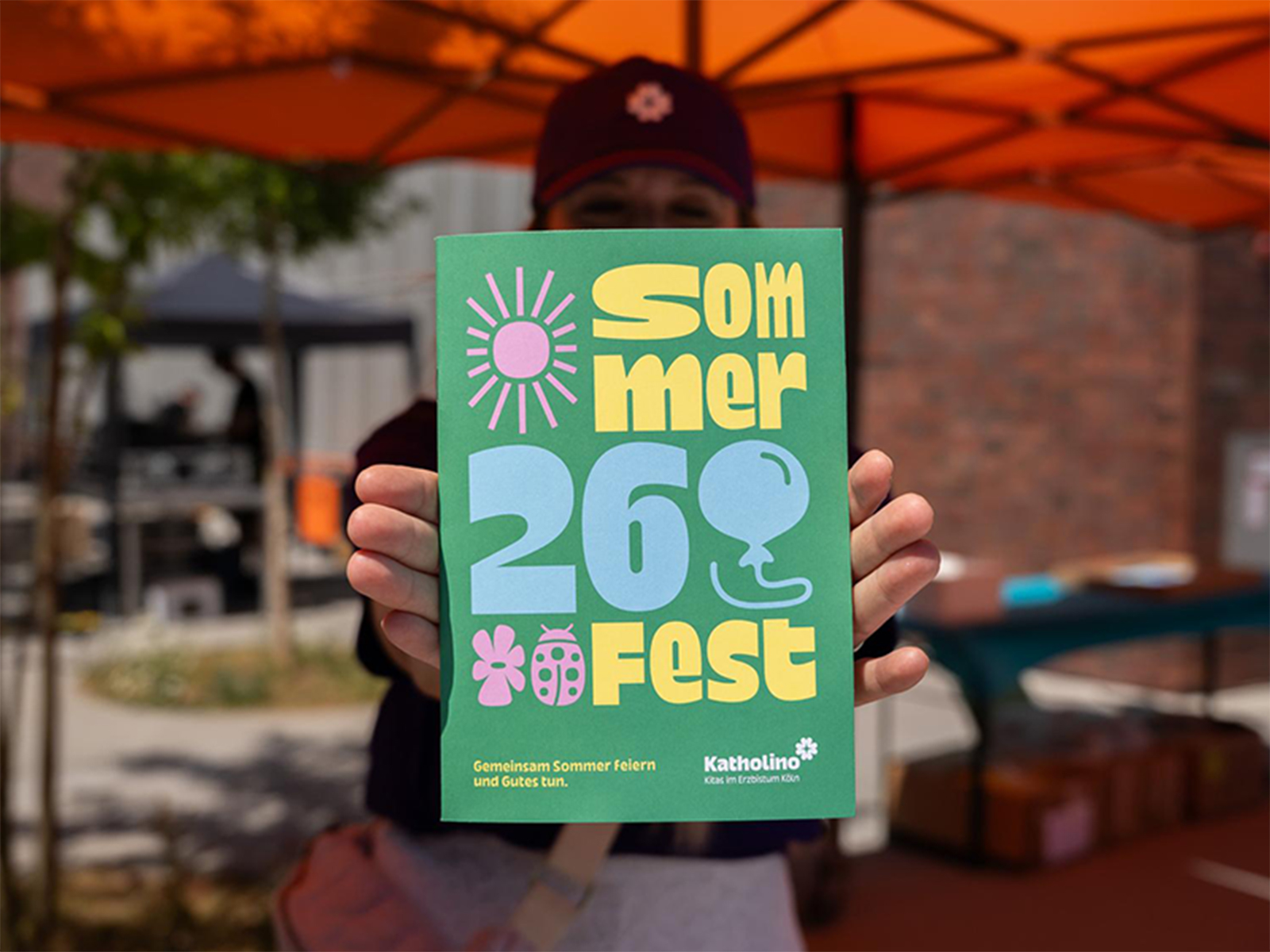 Person hält eine Broschüre für das Sommerfest 2026.